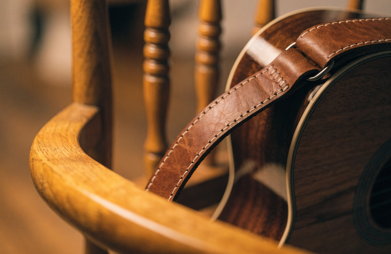 A hand-stitched leather guitar strap on an acoustic guitar